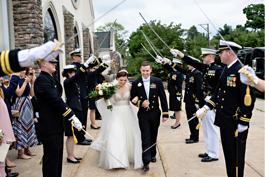 A newly married Navy couple walk through a sword arch after their wedding ceremony.